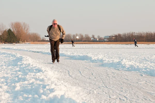 Dutch winter landscape with senior skater on frozen lake. Blue clear sky. Retired man. — Zdjęcie stockowe