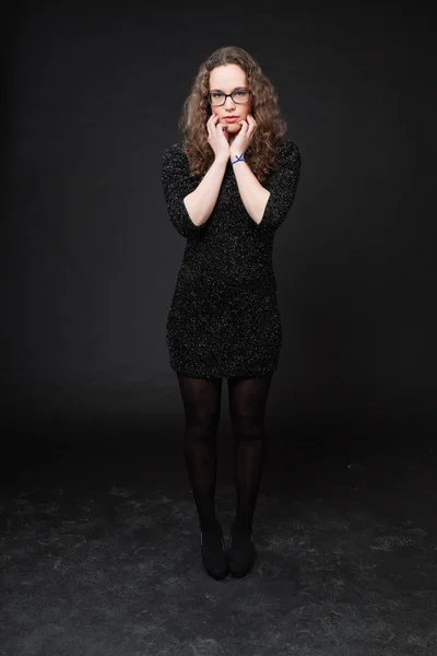 Красивая девушка с длинными кудрявыми волосами. Мода студийный портрет изолирован на черном фоне. В черном платье и очках . — стоковое фото