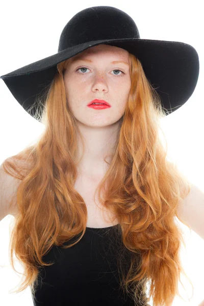 Csinos lány visel, fekete pólót és barna ruhát és fekete kalap hosszú vörös haja. divat stúdió felvétel a elszigetelt fehér háttér. — Stock Fotó