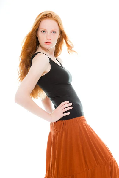 Pretty girl with long red hair wearing black shirt and brown dress. Fashion studio shot isolated on white background. — Stock Photo, Image