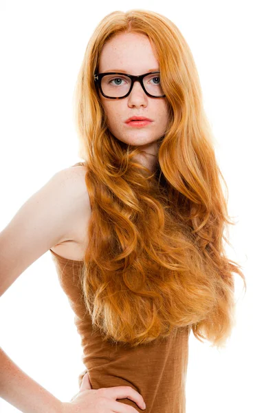 Söt flicka med långa röda hår bär brun skjorta och vintage glas. mode studio skott isolerade på vit bakgrund. — Stockfoto