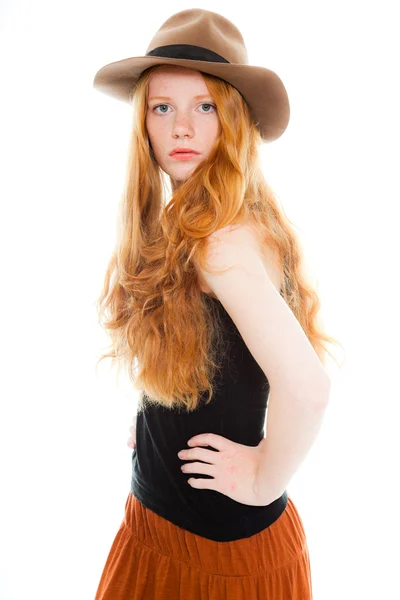Belle fille aux longs cheveux rouges portant une chemise noire et une robe marron et un chapeau marron. Studio de mode tourné isolé sur fond blanc . — Photo