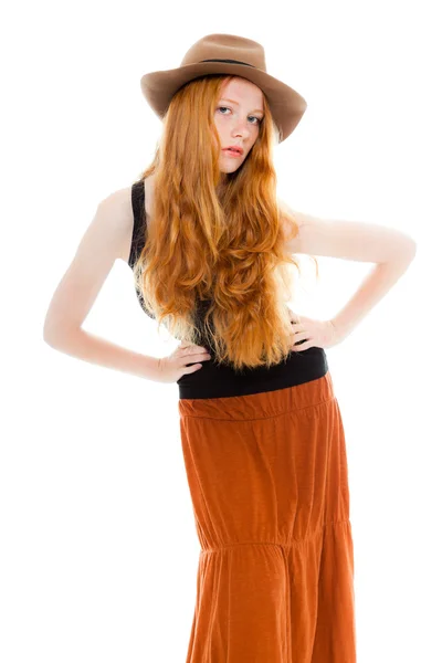 Handsome girl with long red hair wearing black shirt and brown dress and brown hat. Fashion studio shot isolated on white background. — Stock Photo, Image