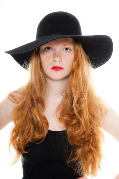 Vacker flicka med långa röda hår bär svart skjorta och bruna klänning och svart hatt. mode studio skott isolerade på vit bakgrund. — Stockfoto