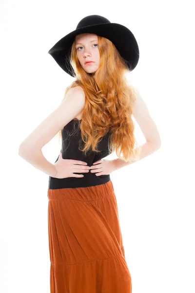 Красивая девушка с длинными рыжими волосами в черной рубашке и коричневом платье и черной шляпе. Студия моды сняла на белом фоне . — стоковое фото