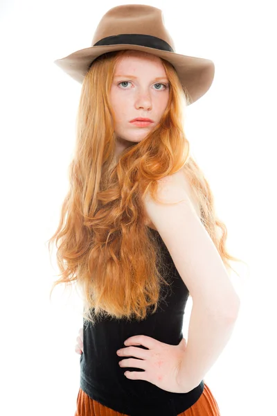 Csinos lány hosszú vörös haja fekete inget és barna ruhát és barna kalapot viselt. divat stúdió felvétel a elszigetelt fehér háttér. — Stock Fotó
