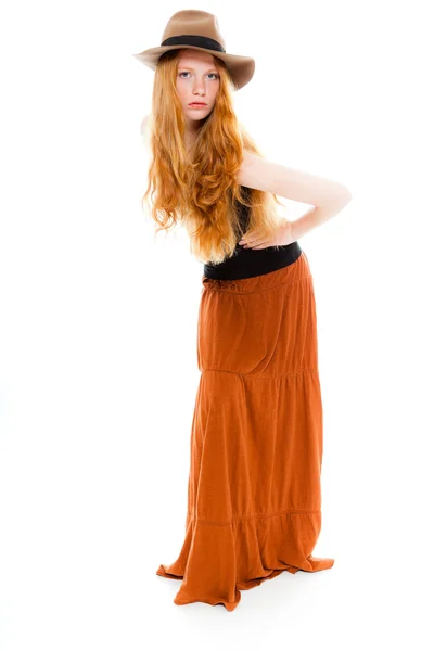 Handsome girl with long red hair wearing black shirt and brown dress and brown hat. Fashion studio shot isolated on white background. Stock Picture