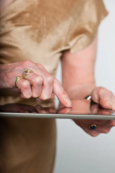 Tablet kullanma kıdemli bir kadının elleri. gri arka plan üzerinde atış studio. — Stok fotoğraf