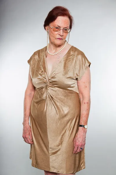Porträtt av bra senior kvinna bär glasögon med uttrycksfulla ansikte visar känslor. Ledsen. agerar unga. Studio skott isolerade på grå bakgrund. — Stockfoto