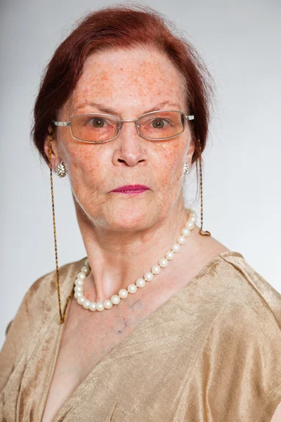 Ritratto di bella donna anziana che indossa occhiali con viso espressivo che mostra emozioni. Si comporta da giovane. Studio girato isolato su sfondo grigio . — Foto Stock