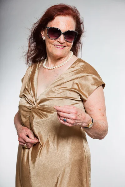Портрет добродушної старшої жінки в сонцезахисних окулярах з виразним обличчям, що демонструє емоції. Щасливий і вільний. Поводитися молодо. Студійний знімок ізольовано на сірому фоні . — стокове фото