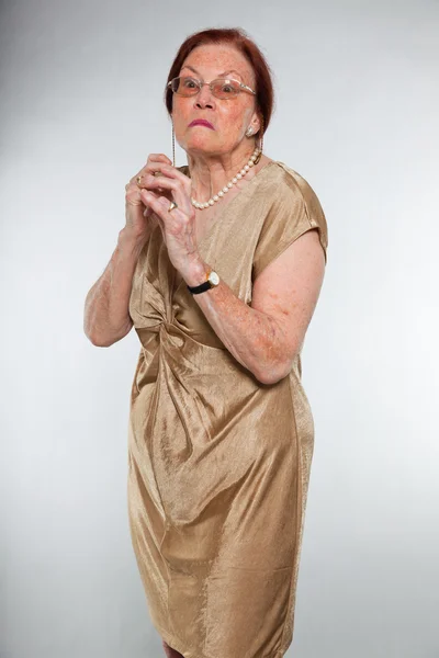 Портрет добродушної старшої жінки в окулярах з виразним обличчям, що демонструє емоції. Наляканий і переляканий. Поводитися молодо. Студійний знімок ізольовано на сірому фоні . — стокове фото