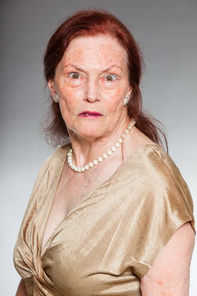 Ritratto di bella donna anziana con volto espressivo che mostra emozioni. Arrabbiato. Si comporta da giovane. Studio girato isolato su sfondo grigio . — Foto Stock