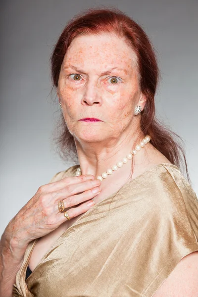 Retrato de mulher idosa de boa aparência com rosto expressivo mostrando emoções. Irritado. A agir jovem. Estúdio tiro isolado em fundo cinza . — Fotografia de Stock