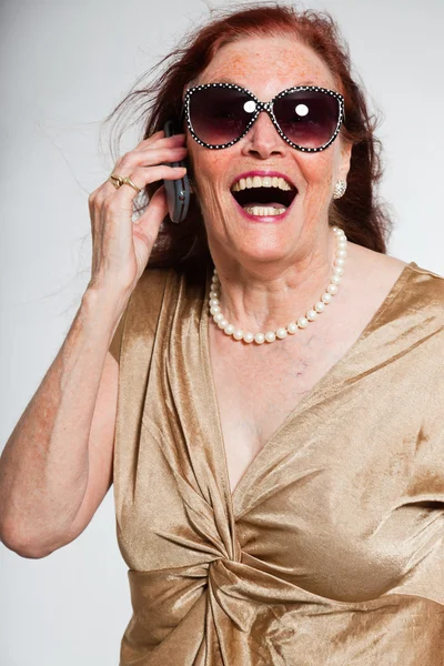 Portret van goed uitziende senior vrouw dragen van een zonnebril met expressief gezicht toont emoties. bellen met mobiele telefoon. handelend jonge. studio opname geïsoleerd op grijze achtergrond. — Stockfoto