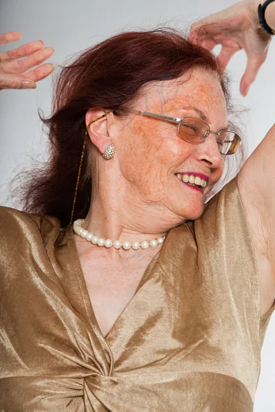 Retrato de una mujer mayor guapa usando gafas con cara expresiva mostrando emociones. Feliz y libre. Actuando joven. Estudio plano aislado sobre fondo gris . — Foto de Stock