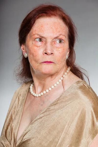 Ritratto di bella donna anziana con volto espressivo che mostra emozioni. Arrabbiato. Si comporta da giovane. Studio girato isolato su sfondo grigio . — Foto Stock