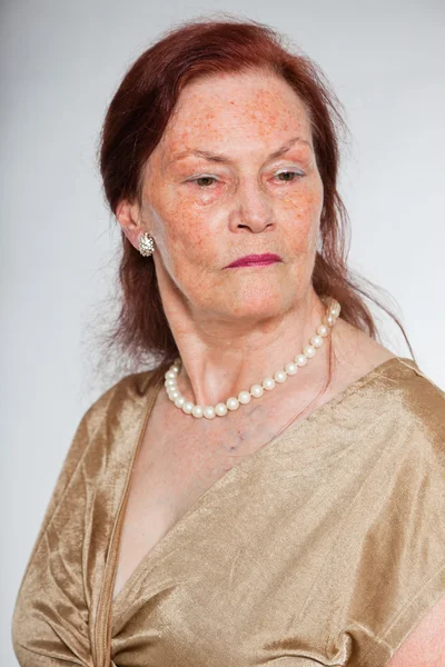 Портрет добродушної старшої жінки з виразним обличчям, що демонструє емоції. Серйозно. Поводитися молодо. Студійний знімок ізольовано на сірому фоні . — стокове фото