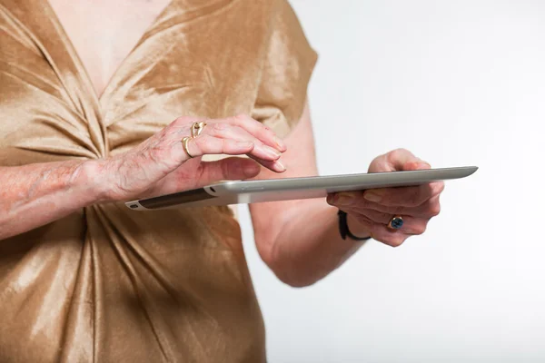 タブレットを使用する年配の女性の手。灰色の背景で撮影スタジオ. — ストック写真