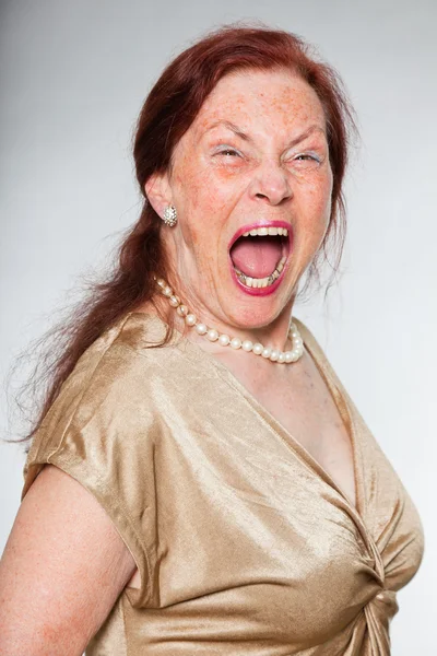 Retrato de mulher idosa de boa aparência com rosto expressivo mostrando emoções. A gritar. A agir jovem. Estúdio tiro isolado em fundo cinza . — Fotografia de Stock