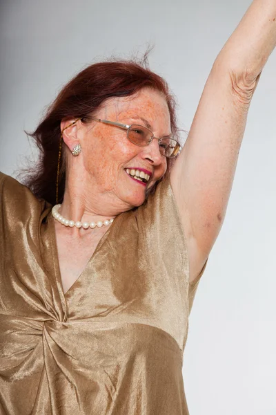 Retrato de una mujer mayor guapa usando gafas con cara expresiva mostrando emociones. Feliz y libre. Actuando joven. Estudio plano aislado sobre fondo gris . — Foto de Stock