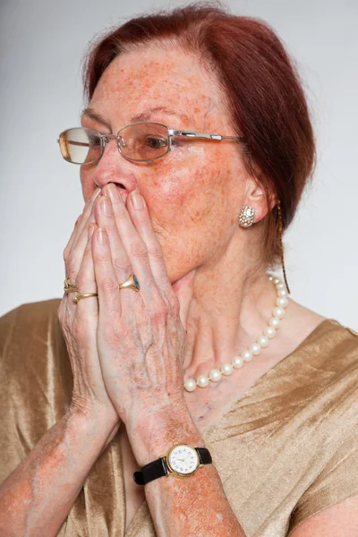 Porträtt av bra senior kvinna bär glasögon med uttrycksfulla ansikte visar känslor. rädd och rädd. agerar unga. Studio skott isolerade på grå bakgrund. — Stockfoto