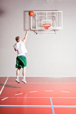 spor salonunda kapalı basketbol zor sağlıklı genç adam. beyaz gömlek ve yeşil şort giyiyor.