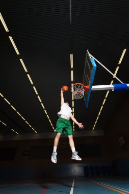 spor salonunda kapalı basketbol zor sağlıklı genç adam. beyaz gömlek ve yeşil şort giyiyor.