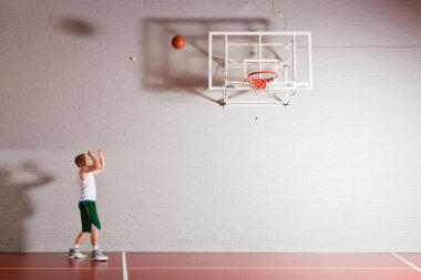 spor salonunda kapalı basketbol zor sağlıklı genç adam. beyaz gömlek ve yeşil şort giyiyor.