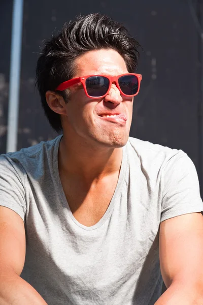 Hombre asiático urbano con gafas de sol rojas haciendo cara divertida. Muy guapo. Un tipo genial. Usar camisa gris . — Foto de Stock