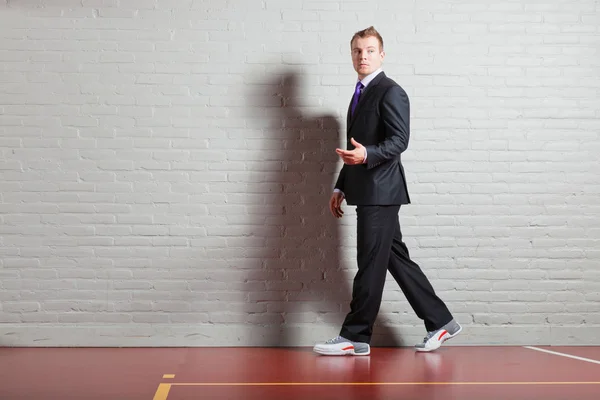 Good looking young man with blond short hair wearing dark suit and basketball shoes. Gym indoor. — Stock Photo, Image