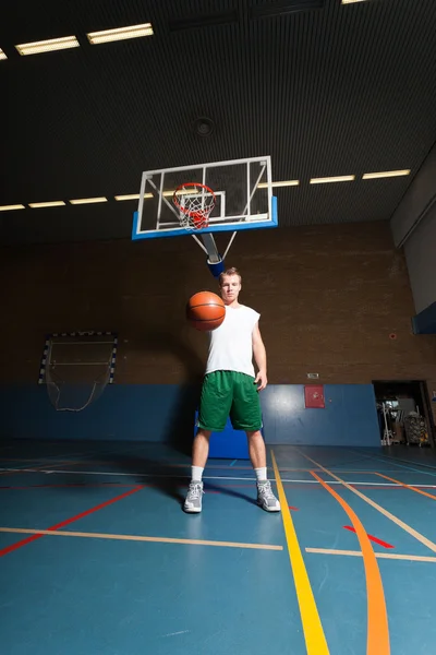 Tuff frisk ung man spelar basket i gym inomhus. bär vit skjorta och gröna shorts. — Stockfoto