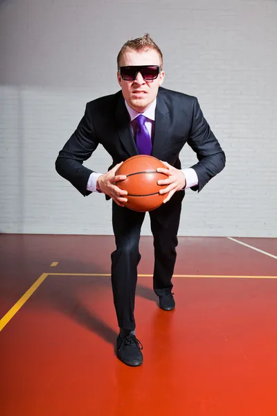 Hombre de negocios enojado con baloncesto. Llevando gafas de sol oscuras. Joven guapo con el pelo corto y rubio. Gimnasio interior . —  Fotos de Stock