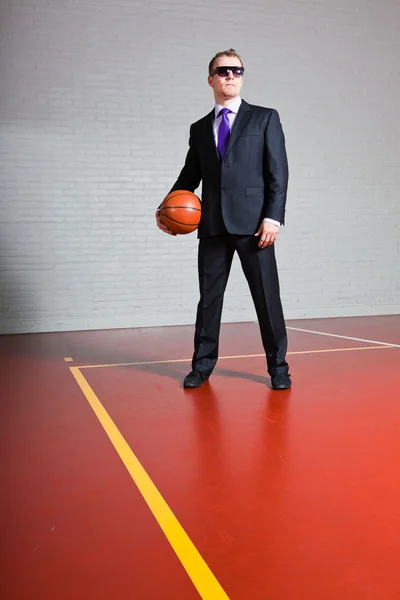Basketbol ile iş adamı. Karanlık güneş gözlüğü takıyor. iyi görünümlü genç adam sarışın kısa saçlı. kapalı spor salonu. — Stok fotoğraf