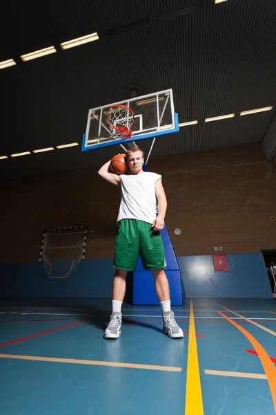 Spor salonunda kapalı basketbol zor sağlıklı genç adam. beyaz gömlek ve yeşil şort giyiyor. — Stok fotoğraf