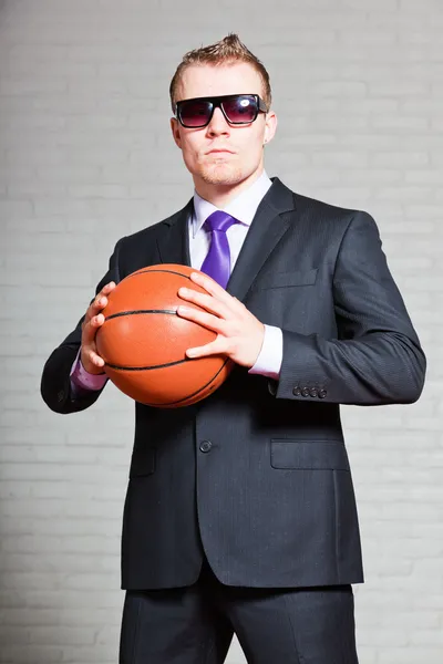 Basketbol ile iş adamı. Karanlık güneş gözlüğü takıyor. iyi görünümlü genç adam sarışın kısa saçlı. Beyaz tuğla duvar. — Stok fotoğraf