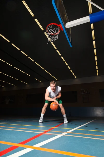 Tuff frisk ung man spelar basket i gym inomhus. bär vit skjorta och gröna shorts. — Stockfoto