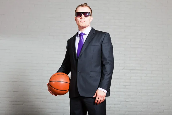 Hombre de negocios con baloncesto. Llevando gafas de sol oscuras. Joven guapo con el pelo corto y rubio. pared de ladrillo blanco . —  Fotos de Stock