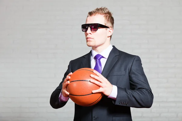 Basketbol ile iş adamı. Karanlık güneş gözlüğü takıyor. iyi görünümlü genç adam sarışın kısa saçlı. Beyaz tuğla duvar. — Stok fotoğraf