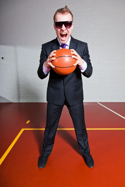 愤怒的业务人打篮球。戴着墨镜。很帅与短的金发的年轻人。室内体育馆. — 图库照片
