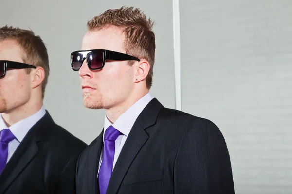 Cool bra letar affärsman med mörka Solglasögon står mot spegeln. — Stockfoto