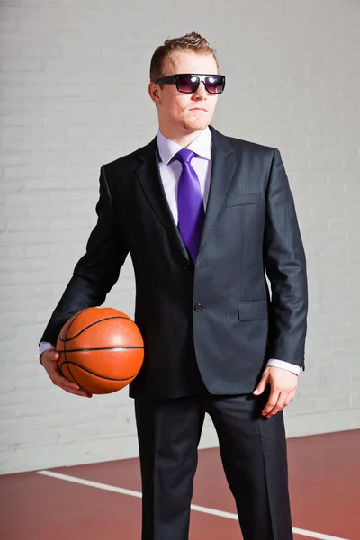 Homem de negócios com basquetebol. A usar óculos escuros. Jovem bonito com cabelo louro curto. Ginásio interior . — Fotografia de Stock