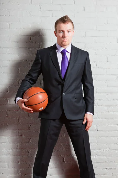 Hombre de negocios con baloncesto. Joven guapo con el pelo corto y rubio. Gimnasio interior . —  Fotos de Stock