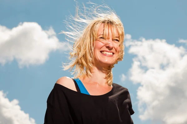 Šťastný pěkné blond žena na pláži. užívat přírodu. modré oblohy jasno. nosí černý svetr. — Stock fotografie