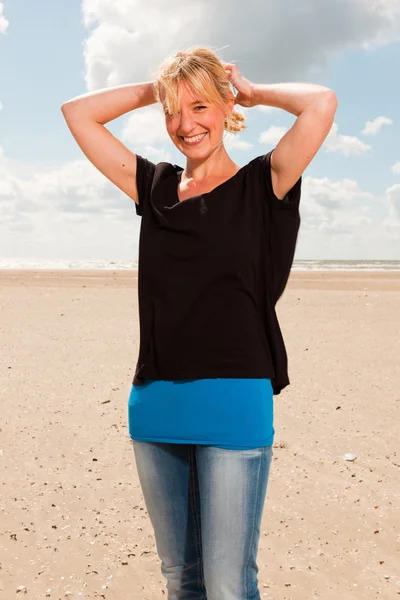 Glückliche hübsche blonde Frau am Strand. Natur genießen. blauer bewölkter Himmel. trägt schwarzen Pullover. — Stockfoto