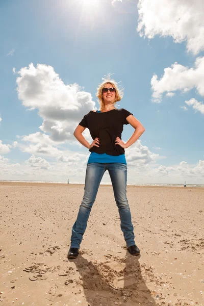 ビーチで幸せなかなり金髪女。自然を楽しんでいます。青い曇り空。黒いセーターとサングラスを着用. — ストック写真