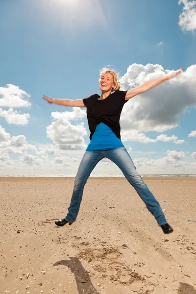 Happy pretty blond woman on the beach. Enjoying nature. Blue cloudy sky. Wearing black sweater. — Stock Photo, Image