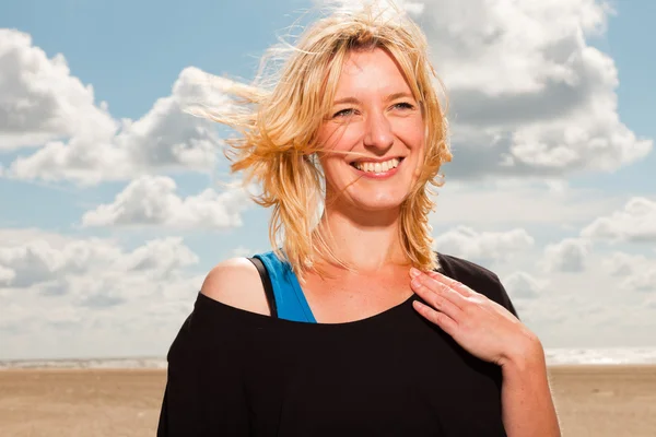 Zadowolony ładny blond kobieta na plaży. korzystających z natury. błękitne niebo pochmurne. ubrana w czarny sweter. — Zdjęcie stockowe