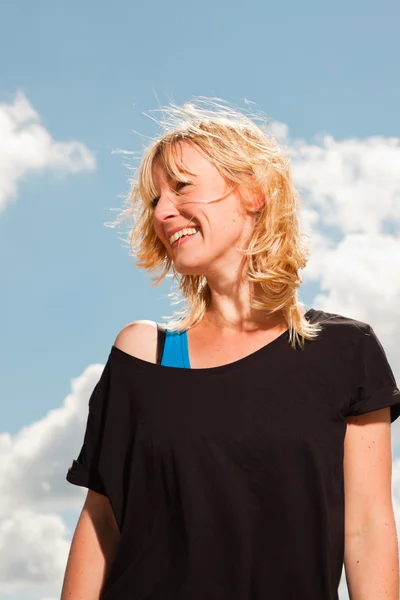 Glückliche hübsche blonde Frau am Strand. Natur genießen. blauer bewölkter Himmel. trägt schwarzen Pullover. — Stockfoto