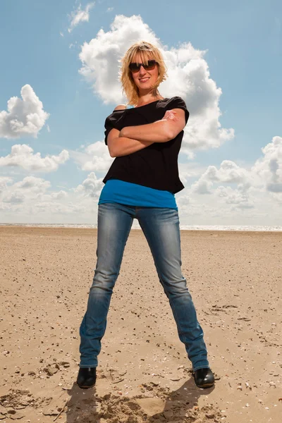 해변에서 행복 한 예쁜 금발 여자입니다. 즐기는 자연. 푸른 흐린 하늘입니다. 블랙 스웨터와 선글라스 입고. — 스톡 사진